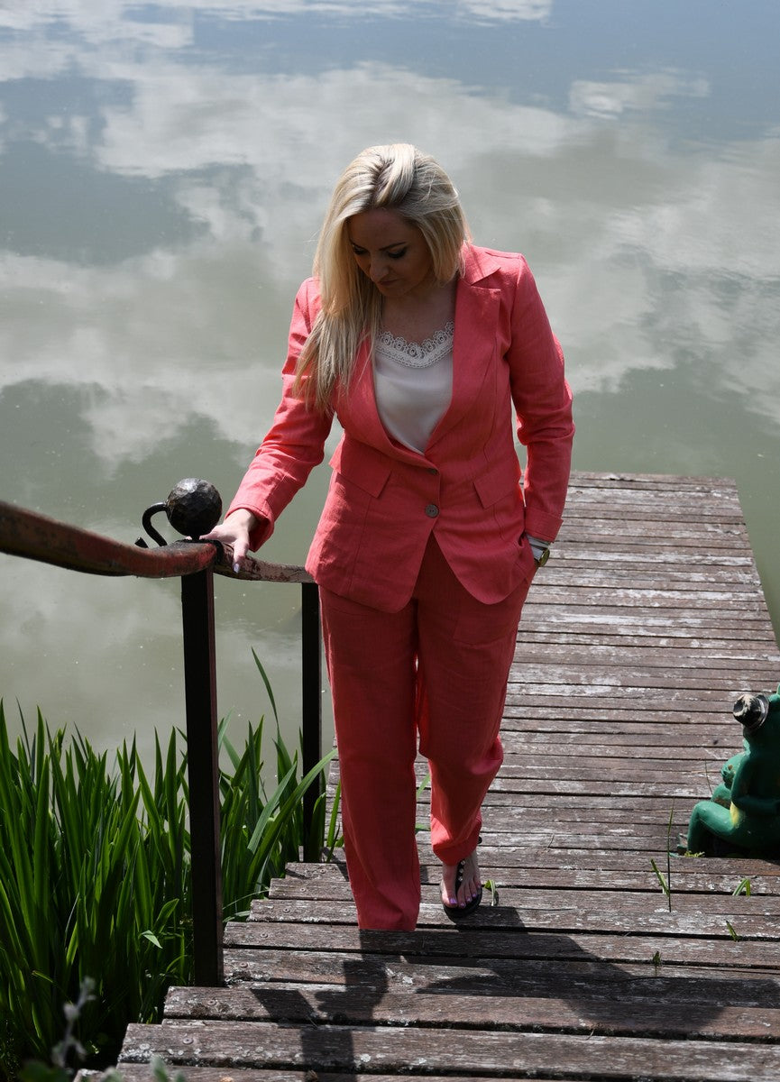 Koralinės spalvos lininis kostiumėlis moterims AISTĖ. Elegantiškas, dviejų dalių: klasikinis švarkas ir kelnės su kišenėmis.