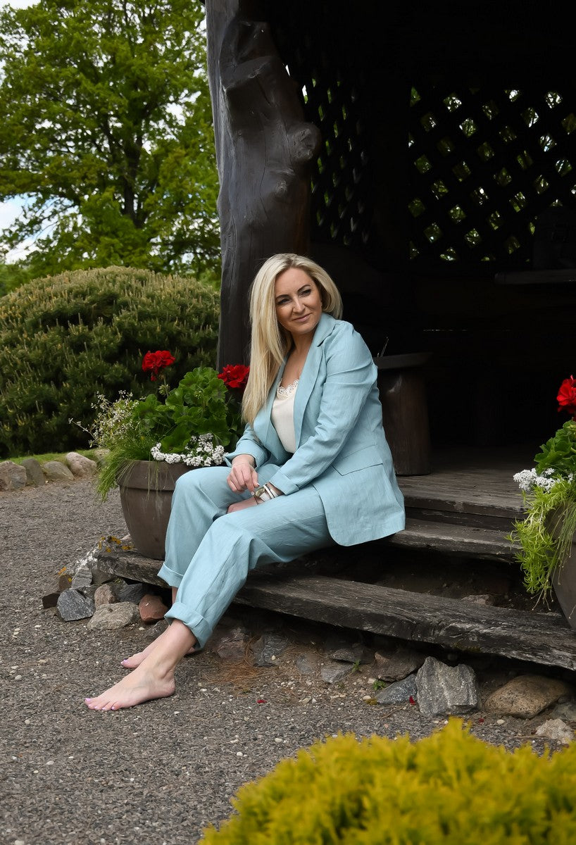 Žydros spalvos lininis kostiumėlis moterims AISTĖ. Elegantiškas, dviejų dalių: klasikinis švarkas ir kelnės su kišenėmis.